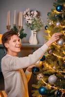 Smiling guy decorating Christmas tree. photo