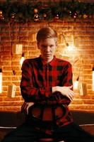 Young guy with serious face on high chair in Christmas decorations. photo