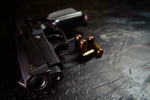 Pistol with cartridges on black concrete table.