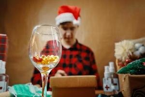 Glass with vitamins in close-up and man in Santa hat in background. photo