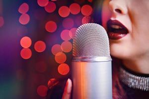 Woman singer with disco mic on bokeh light background. photo
