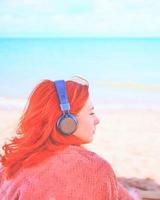 hermosa mujer escuchando música en la playa. foto