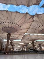 Medina, Saudi Arabia, 2022 - Umbrella construction on the square of Al-Masjid An-Nabawi or Prophet Muhammed Mosque are protecting people from sun at daytime and work as lights at night photo