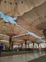 Medina, Saudi Arabia, 2022 - Umbrella construction on the square of Al-Masjid An-Nabawi or Prophet Muhammed Mosque are protecting people from sun at daytime and work as lights at night photo