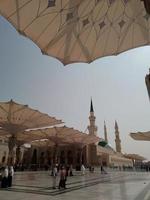 Medina, Saudi Arabia, 2022 - Umbrella construction on the square of Al-Masjid An-Nabawi or Prophet Muhammed Mosque are protecting people from sun at daytime and work as lights at night photo