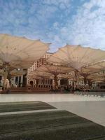 Medina, Saudi Arabia, 2022 - Umbrella construction on the square of Al-Masjid An-Nabawi or Prophet Muhammed Mosque are protecting people from sun at daytime and work as lights at night photo