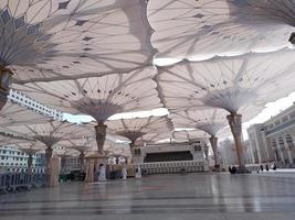 Medina, Saudi Arabia, 2022 - Umbrella construction on the square of Al-Masjid An-Nabawi or Prophet Muhammed Mosque are protecting people from sun at daytime and work as lights at night photo