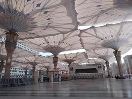 Medina, Saudi Arabia, 2022 - Umbrella construction on the square of Al-Masjid An-Nabawi or Prophet Muhammed Mosque are protecting people from sun at daytime and work as lights at night photo