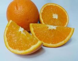 Cut and whole fresh ripe oranges on white background photo