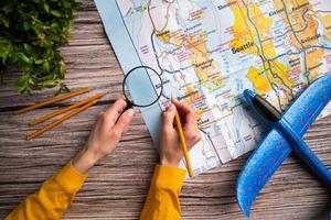 woman hand drawing on travel map, planning trip or vacation photo