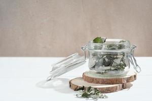 transparent glass jar with dry raspberry leaves for herbal tea. herbs for fever relief tea. ingredients for alternative medicine, pantry storage photo