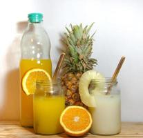 Juices smoothies and fresh pineapple and orange drinks with summer fruits photo