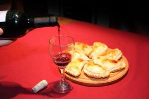 serving wine in the glass with empanadas plate typical South American food photo