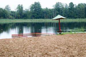 A lone, sagging sunken umbrella and fencing, a playpen for bathing children on a sandy beach on the shore of a lake, a river at a recreation center, a sanatorium in the fall on a cloudy day photo