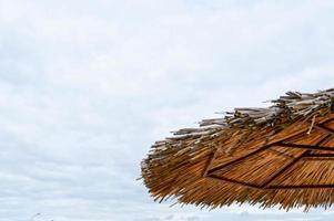 Texture of a natural straw dry beach sun umbrella made from hay dried grass and branches on the beach against a blue sky at a rest resort photo