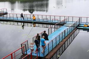 People, men are fishing from the pontoon, apron, bridge on the lake with ducks at the recreation center, sanatoria in the fall photo