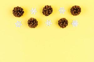 Top view of holiday composition made of pine cones and white snowflakes on colorful background. Winter time and Christmas concept with copy space photo