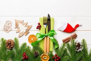 Top view of utensils on festive napkin on wooden background. Christmas decorations with dried fruits and cinnamon. New year dinner concept with copy space photo