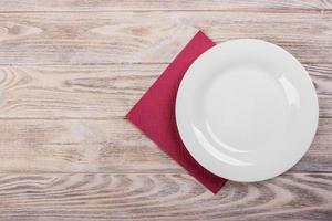 Empty plate on wooden tabletop with tablecloth photo
