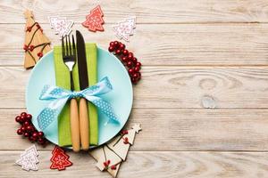 Top view of plate, fork and knife served on Christmas decorated wooden background. New Year Eve concept with copy space photo