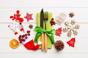 Top view of fork and knife on napkin on wooden background. Different christmas decorations and toys. New Year dinner concept with empty space for your design photo