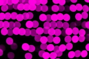 Unfocused abstract purple bokeh on black background. defocused and blurred many round light photo