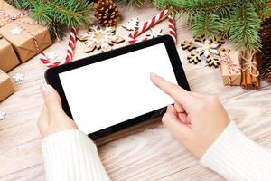 Tablet computer in girl hands. tablet computer with red gift box, christmas candy and fir branches. Free space for text. top view. Copy space. Closeup photo