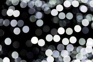 Bokeh white lights on black background, defocused and blurred many round light on background photo