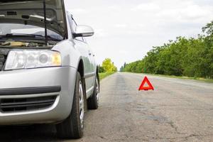 Red triangle of a car on the road. Car warning triangle on the road against the city in the evening. photo