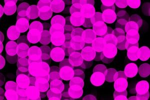 Unfocused abstract violet bokeh on black background. defocused and blurred many round light photo