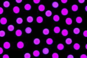 Unfocused abstract purple bokeh on black background. defocused and blurred many round light photo