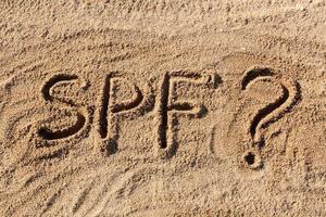 Sun protect factor concept. SPF word written on the beach with question mark photo