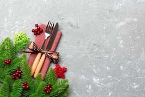 Top view of christmas decorations on cement background. Fork and knife on napkin tied up with ribbon and empty space for your design. New year pattern concept photo