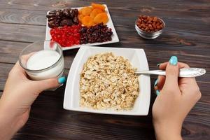 the girl cooked her muesli for breakfast. the girl eats oatmeal porridge that would lose weight and maintain a diet. Useful and healthy breakfast. dark wooden background, top view photo