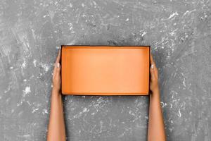 Girl hands holding open empty box on gray background photo