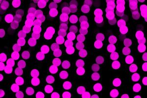 Unfocused abstract purple bokeh on black background. defocused and blurred many round light photo