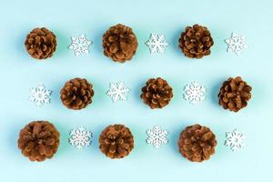 Top view of holiday composition made of pine cones and white snowflakes on colorful background. Winter time and Christmas concept with copy space photo