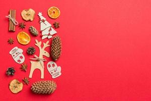 Top view of red background decorated with festive toys and Christmas symbols reindeers and New Year trees. Holiday concept with copy space photo
