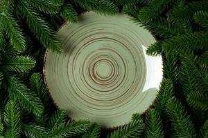 Top view holiday plate among green fir tree branches. Christmas dinner with copy space photo