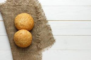 Several small multi grain triangular shaped bread sprinkled with whole sunflower seeds, flax and sesame seeds on a sackcloth photo