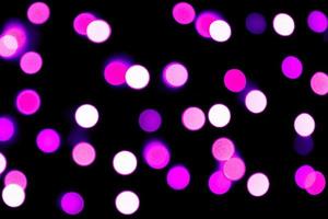 Unfocused abstract purple bokeh on black background. defocused and blurred many round light photo