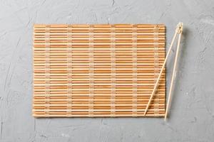 two sushi training sticks with empty bamboo mat or wood plate on stone Background Top view with copy stace photo