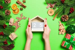 Top view of female hands holding calendar on green background. The twenty fifth of December. Holiday decorations. Christmas time concept photo