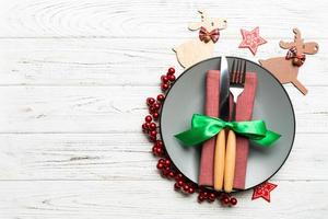Top view of plate, fork and knife served on Christmas decorated wooden background. New Year Eve concept with copy space photo