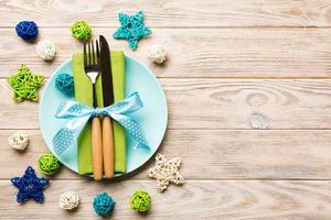 Holiday composition of Christmas dinner on wooden background. Top view of plate, utensil and festive decorations. New Year Advent concept with copy space photo