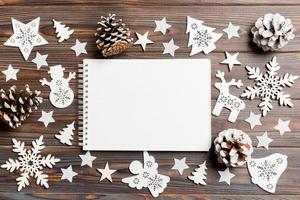 Top view of notebook on wooden background made of Christmas decorations. New Year concept photo