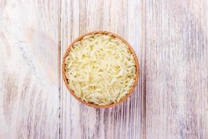 Rice in a bowl. Bowl with rice on a wooden oak background, cutting board, top view. photo