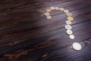 question mark from coins of different countries on a wooden background photo