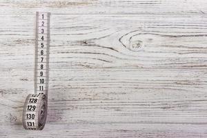 Medidor de sastrería cinta métrica blanca sobre fondo de madera foto