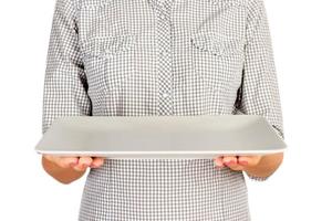 girl in the plaid shirt is holding an empty rectangular matte plate in front of her. woman hand hold empty dish for you desing. perspective view, isolated on white background photo